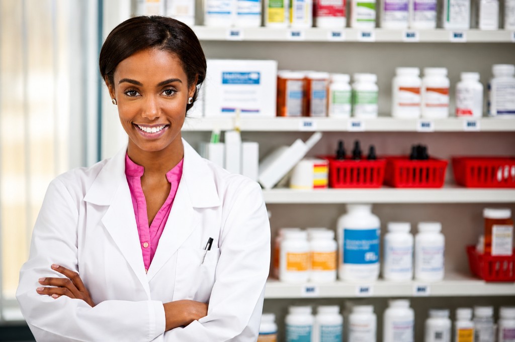Professional pharmacist in a lab coat standing in a well-stocked pharmacy