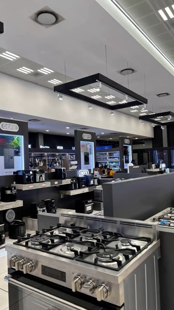 Modern appliance retail showroom with kitchen ranges, coffee machines, and display shelving