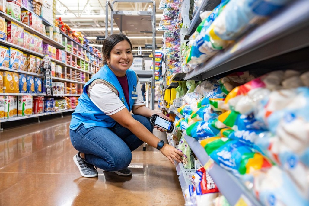 Supermarket employee scanning inventory with a handheld device in a grocery aisle