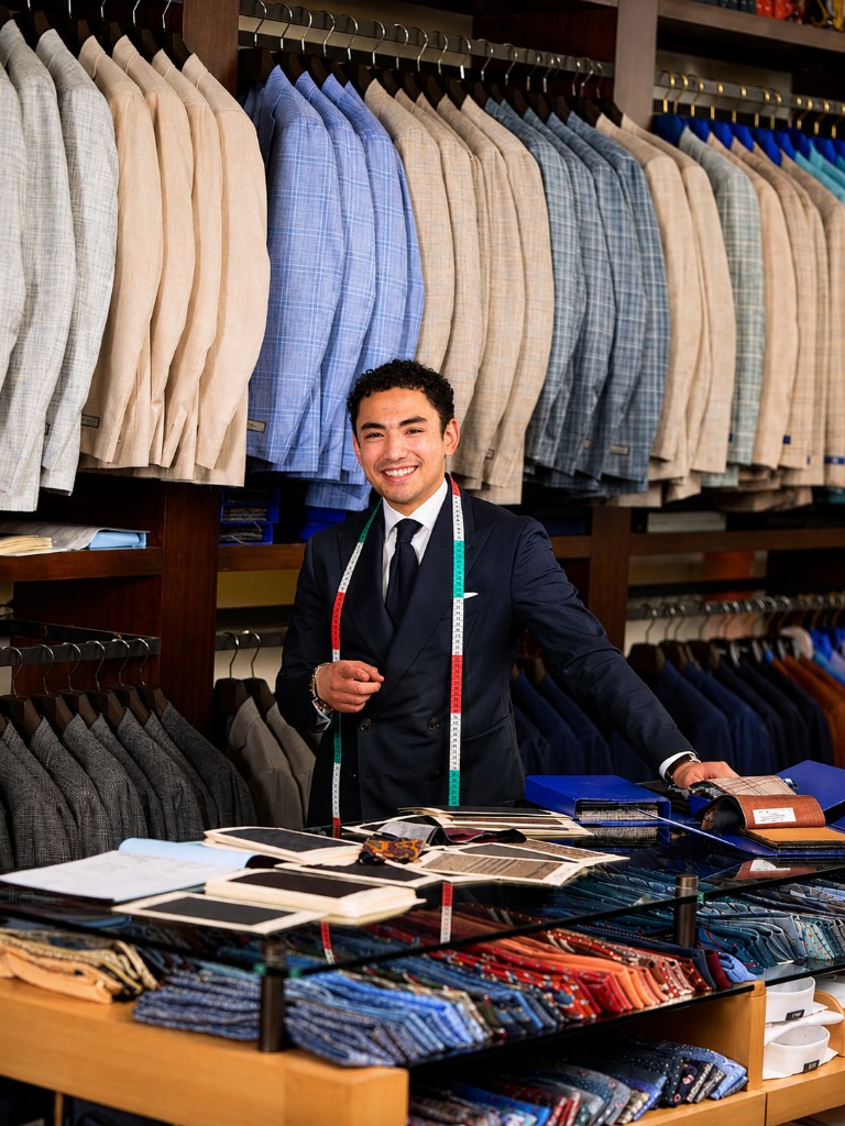 Professional tailor with measuring tape in a bespoke menswear shop